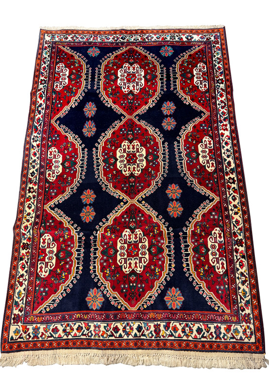 Edge of a Persian Qashqai rug highlighting the detailed border patterns with geometric and floral designs in a multicolor scheme on a white fringe background