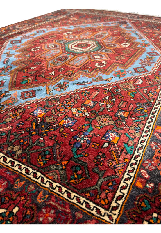 Angled view of a Persian Gholtogh Rug displaying the symmetry of the design and the variation of red and blue hues