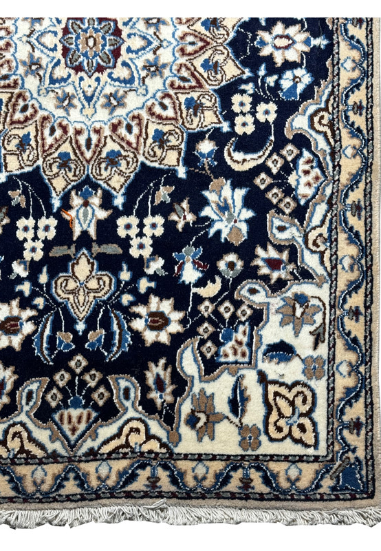 Corner detail of the Persian Nain rug with fringe, showcasing the precision of the guard bands and motifs