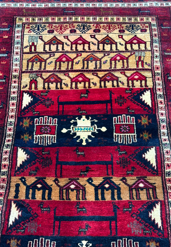Focused image of the midsection of a Persian Baluch Tribal rug displaying symmetric tribal patterns and motifs