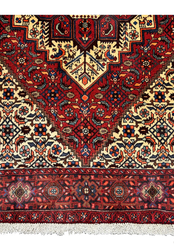 Close-up of the Persian Gholtogh rug's detailed geometric motifs and deep red background