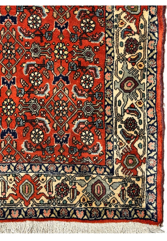 The corner of the vintage Bijar rug showing the border and fringe, alongside the central pattern.