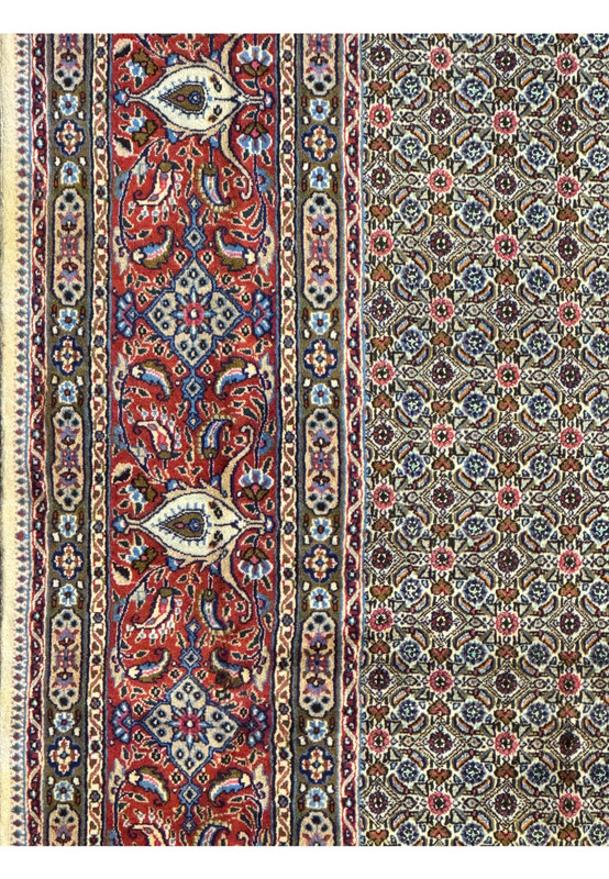 Side view of the Persian Moud Rug focusing on the multicolored fringe and the finely knotted edge of the border.