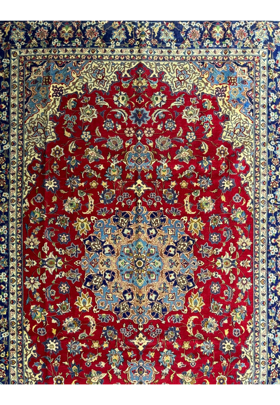 A detailed view of the Persian Isfahan rug's central design, focusing on the dense floral patterns and the ornate medallion with its complex layering of blue, gold, and cream on a rich red base