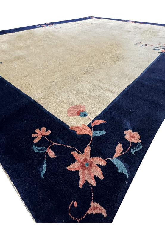 Angled perspective of an 8'2" x 11'2" Vintage Art Deco Rug, emphasizing the depth of the navy border against the ornamental beige center