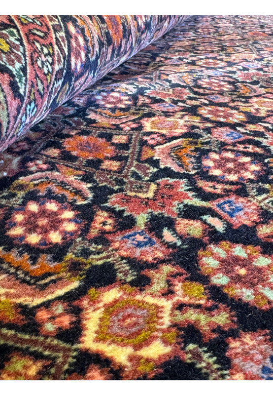 Close-up view of Persian Bijar rug's texture, displaying the plush pile and intricate weaving patterns with a variety of warm, autumnal colors