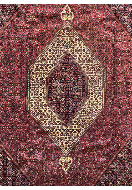 Detailed view of the Persian Bijar rug's central medallion, featuring an intricate cream pattern against a rich red background.