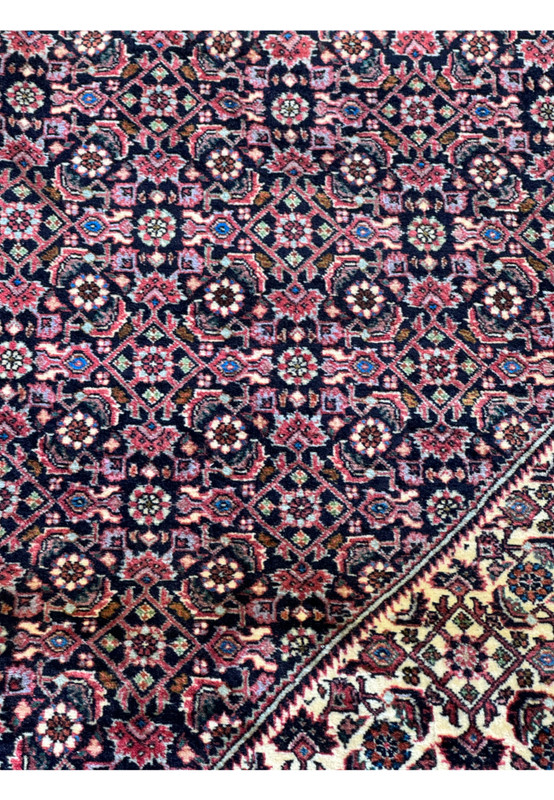 A close-up on the corner detailing of the Persian Bijar rug, illustrating the tight weave and rich color saturation of the wool.