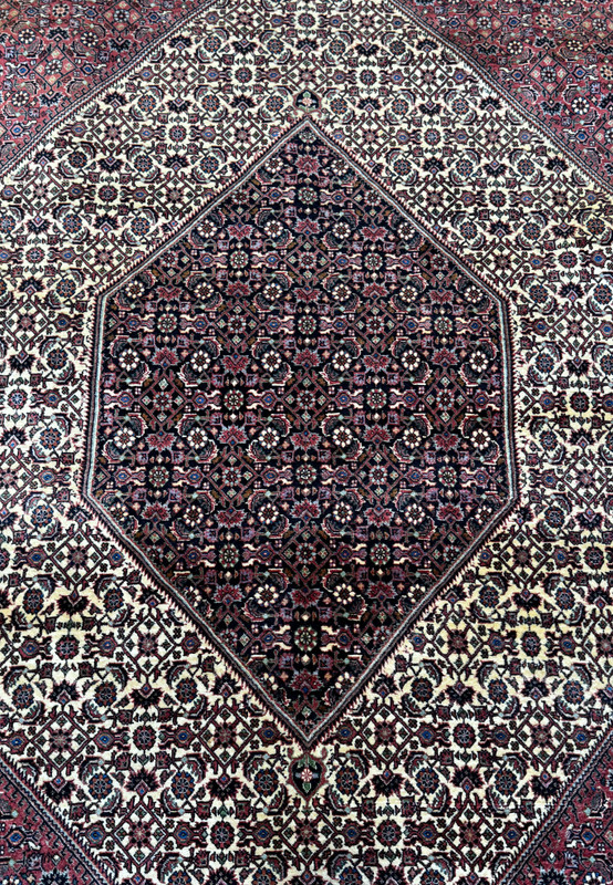 An overhead view of a Persian Bidjar rug, highlighting the central diamond medallion set against a detailed field of dark and light patterns
