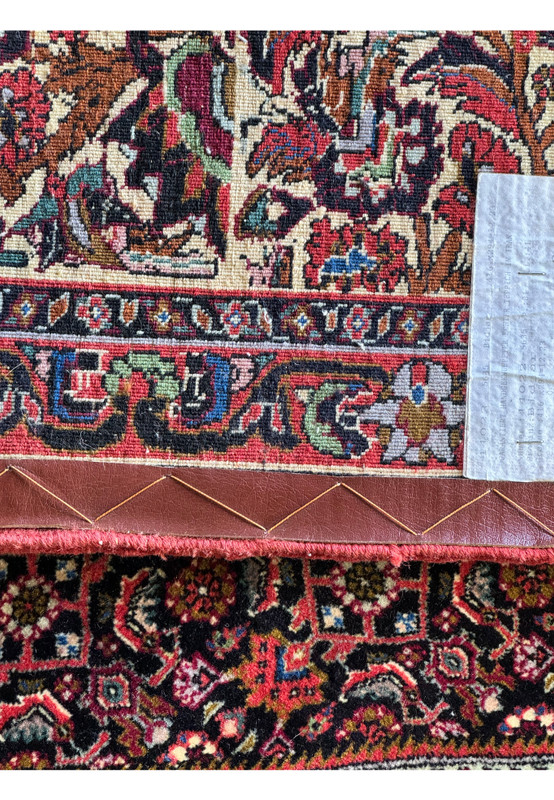 A close-up view of the Bijar rug, with the quarter placed at the transition where the rug’s edge meets the leather binding, illustrating the rug's thickness and the precision of the pattern's edge