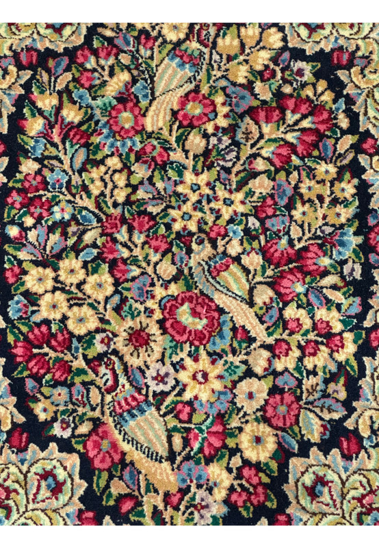 Close-up of the intricate floral pattern on a Persian Kerman rug, highlighting the vibrant colors and detailed weaving