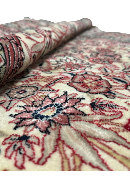 Image showing a folded section of the Persian Qum rug, illustrating the thickness and quality of the weave, with a glimpse of the detailed floral patterns and the soft sheen on the fabric.