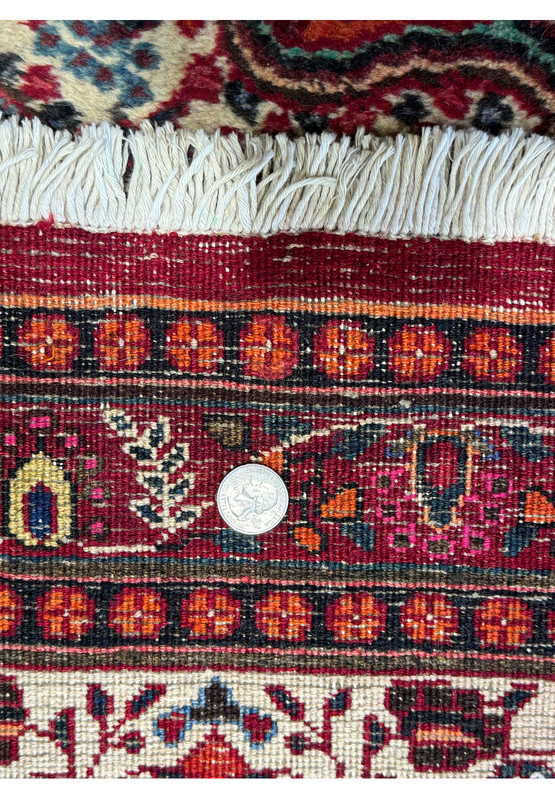 Close-up of the Persian Moud Rug's border, with a quarter placed for scale, showcasing the meticulous detail and rich heritage of Moud weaving technique