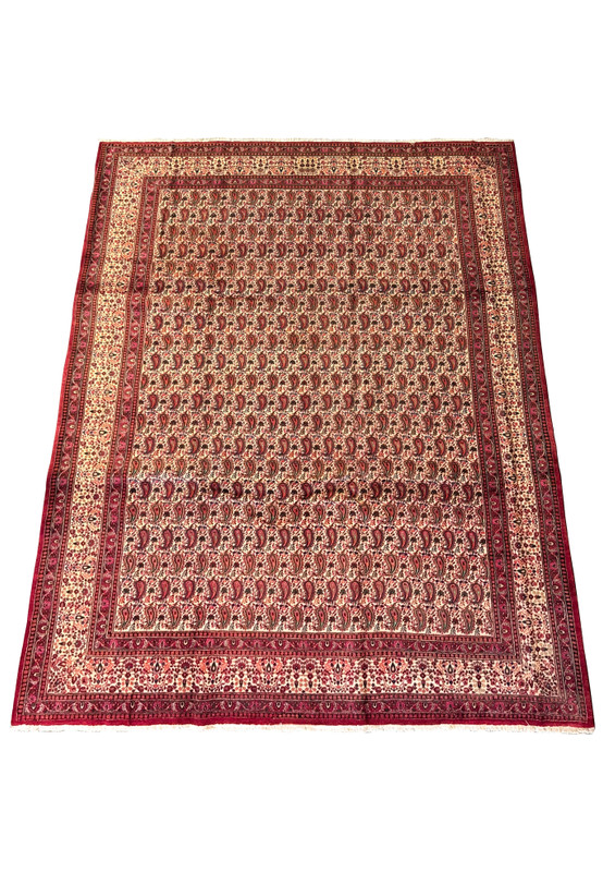 Overhead view of a Persian Moud Rug laid flat, showcasing intricate Herati patterns with a rich red and blue color palette on a cream background, bordered by detailed ornamental designs