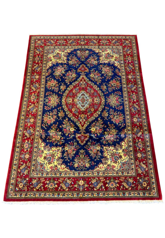 Angled view of a Persian Qum Kork and Silk Rug, highlighting the plush texture and intricate weaving of floral and vine motifs in rich colors on a navy field.