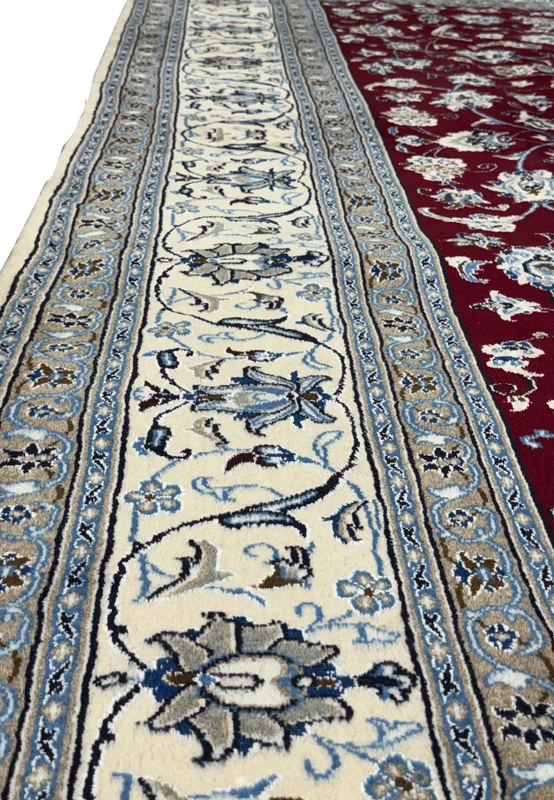 Detailed shot of the Persian Nain 9La rug's center, showing the complex interplay of floral designs and the plush texture of wool and silk