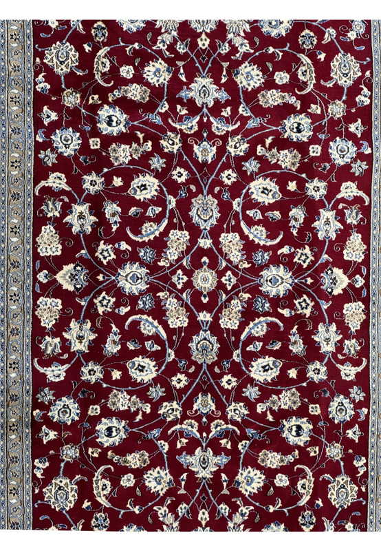 Close-up of the central pattern of the Persian Nain 9La rug, highlighting the detailed floral designs in cream and blue on a rich red background