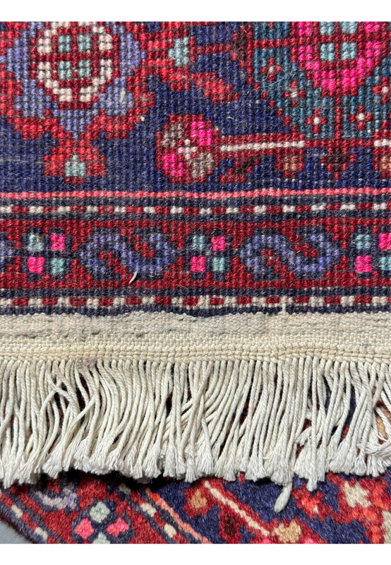 Close-up of the fringe and edge of a 3'4" x 5'1" Persian Gholtogh Rug. The detailed geometric and floral patterns in vibrant red and navy blue, along with the pastel accents, highlight the traditional Persian craftsmanship and high-quality hand-knotted construction
