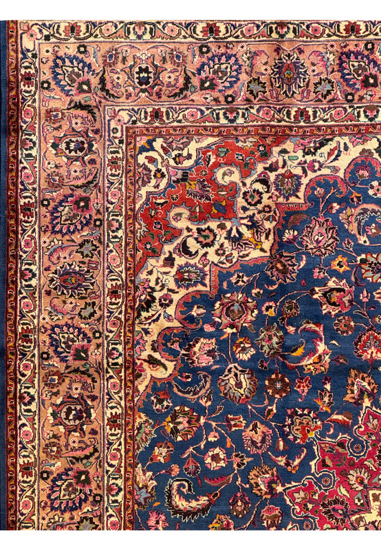 Close-up of the corner of a Persian Mashad Rug, showing detailed floral patterns and contrasting border designs