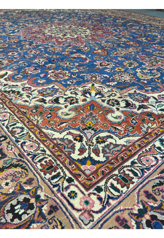 Side view of a Persian Mashad Rug, focusing on the depth of the intricate floral and vine designs in the central field.