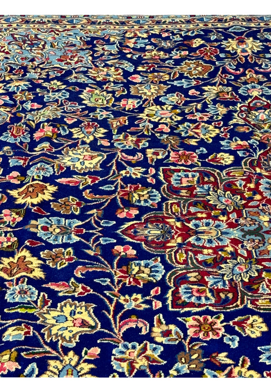 Focused view of the upper corner of a Persian Kerman Rug, emphasizing the detailed floral border and the harmonious color palette that highlights the craftsmanship