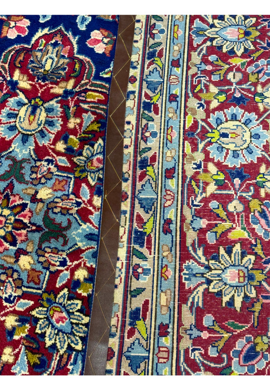 Close-up of the back side of a Persian Kerman Rug with a coin placed for scale, illustrating the fine knotting and weaving quality typical of Kerman rugs