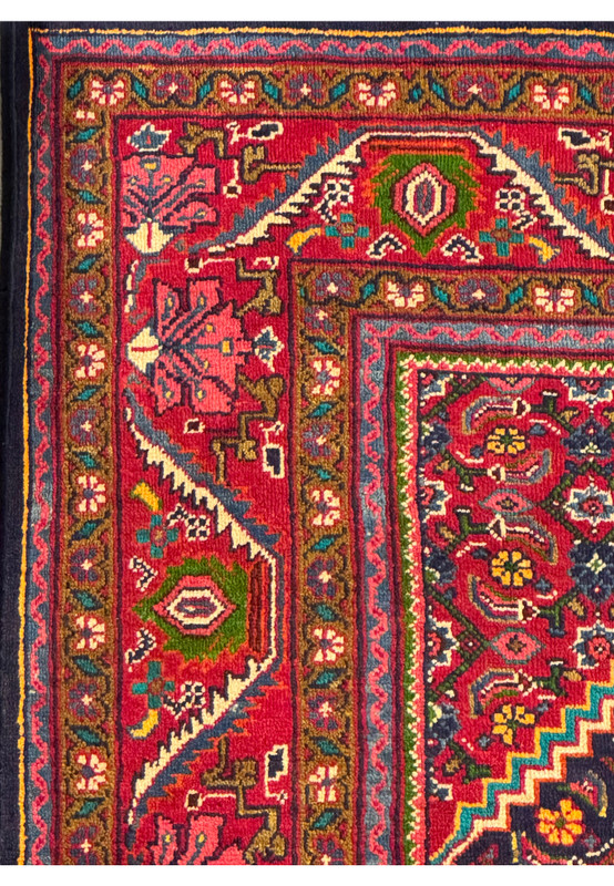 Corner view of a Persian Mahal Rug, displaying the detailed border and the vibrant central field patterns in navy, red, and gold. The intricate geometric and floral designs are meticulously hand-knotted, reflecting the high quality and craftsmanship of the rug. This view emphasizes the harmonious blend of colors and the luxurious feel of the wool, making it an elegant addition to any living space.