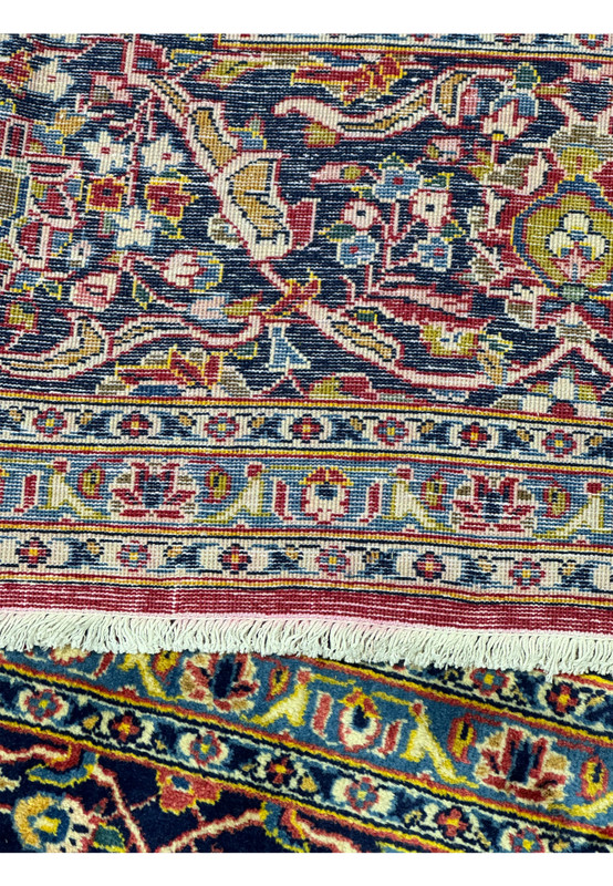 Close-up of the back of a Persian Kashan rug, highlighting the detailed knotting and craftsmanship. The reverse side reveals the intricate patterns and color palette used in the rug's design. The high knot density and quality of materials are apparent, showcasing the durability and meticulous construction of this Persian rug. This image provides insight into the traditional weaving techniques used in Kashan rugs.