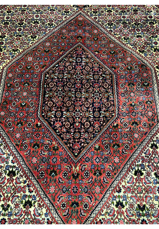 Close-up of the medallion on a 9.8 x 12.2 Persian Bijar rug highlighting precise knot work, deep saturated reds, navy outlines, and crisp geometric symmetry.