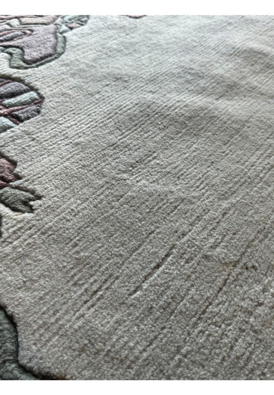 Close-up of the artistic border design on the Nepal rug, displaying a mix of abstract shapes in muted tones with a sculpted finish.