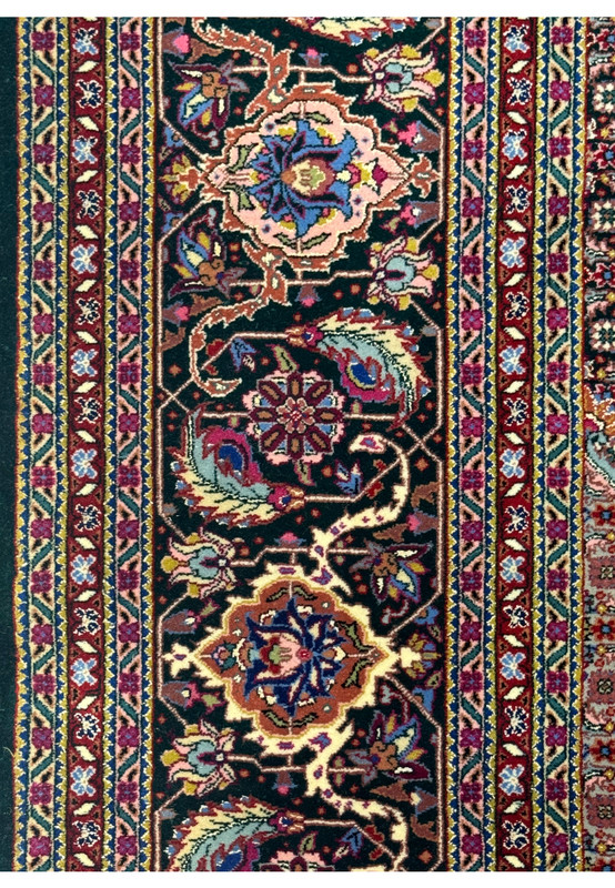 Close-up of the floral border design in the Tabriz rug with repeating vine and flower patterns.