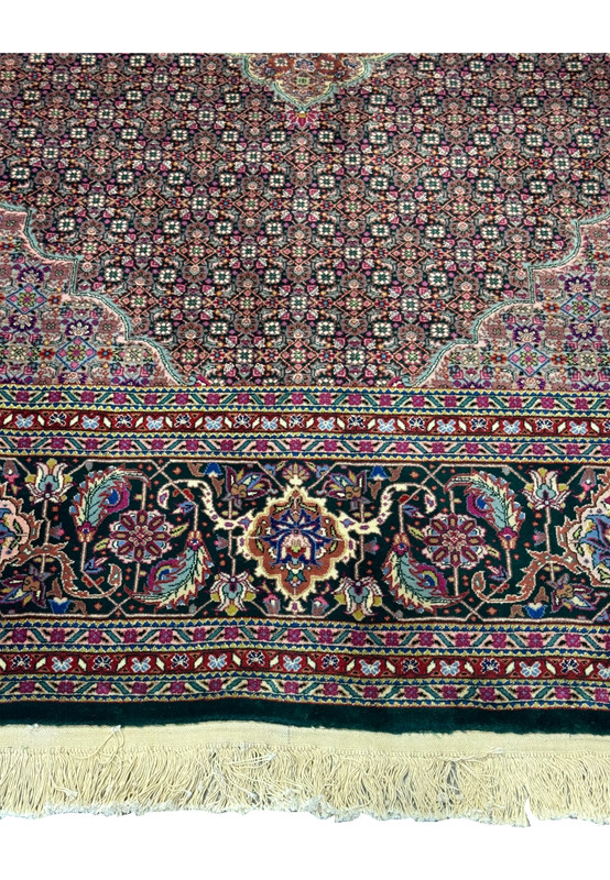 View of the lower edge of the rug, showing the fringe and part of the border.