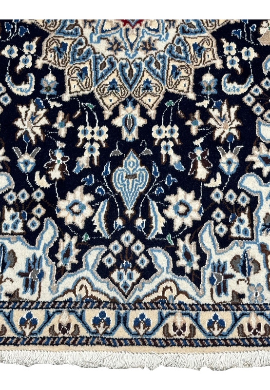 Lower portion of Persian Nain rug featuring floral motifs on a deep navy background framed by light blue and ivory borders.