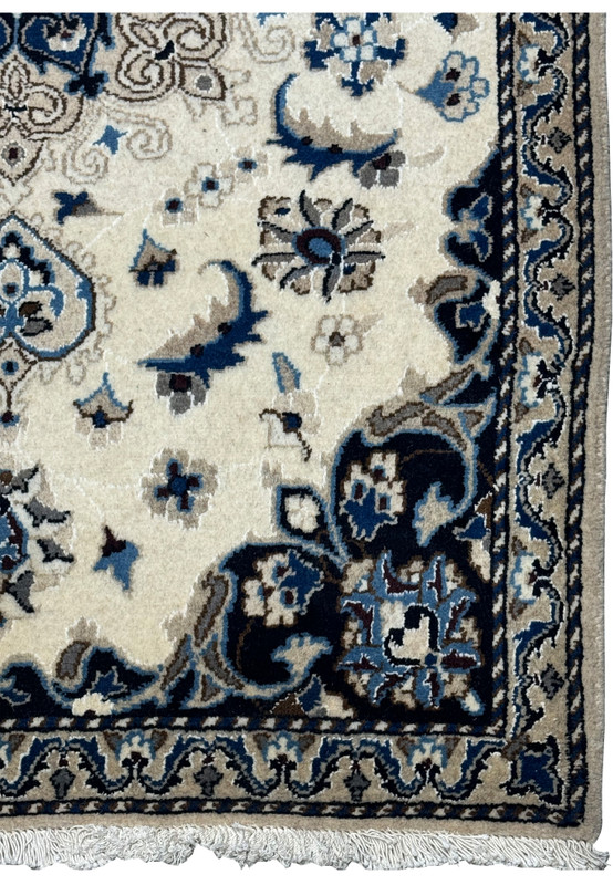 Close-up of the border of the Nain Persian rug with detailed floral designs in navy blue and beige, framed by intricate patterns.