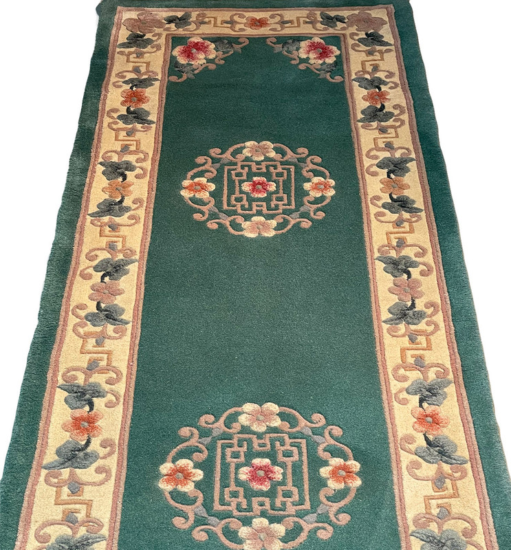 Upper part of the runner showing floral medallion details and cream borders with teal field.