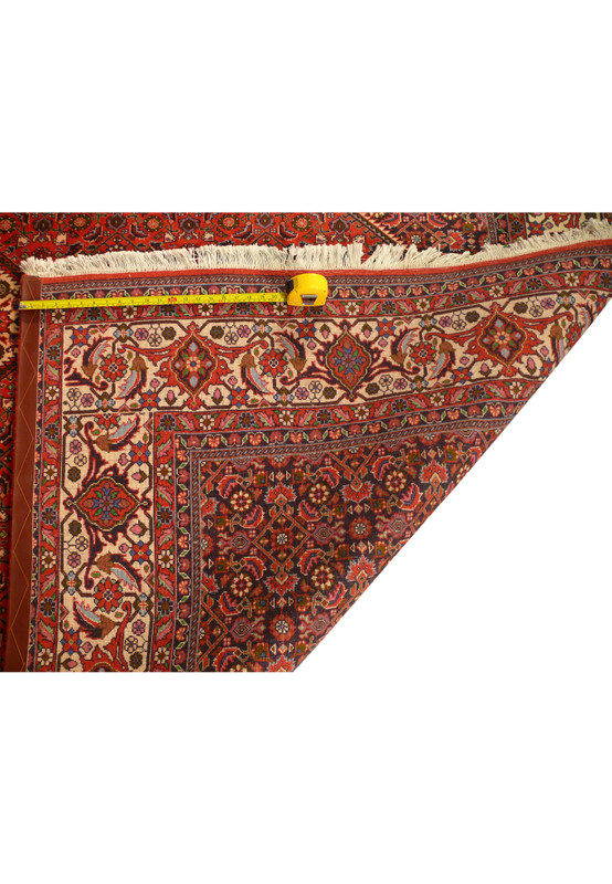 Back of Bijar rug folded to show fine knots, sturdy selvage, and tape measure for scale.