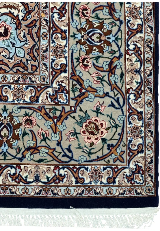 Close-up of Persian rug border with floral and arabesque patterns in sage, ivory, and pink tones