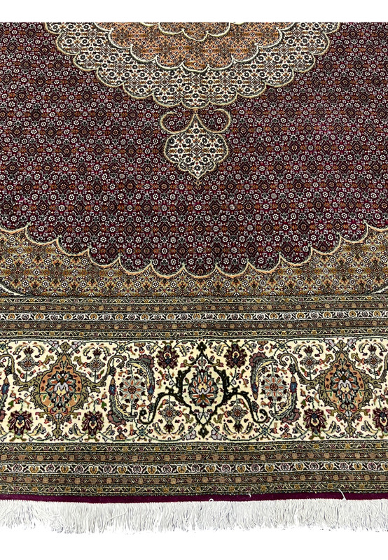 Corner edge of 10x10 Persian Tabriz 50 Raj rug with ivory border, burgundy ground, and white fringes showcasing handmade finishing.