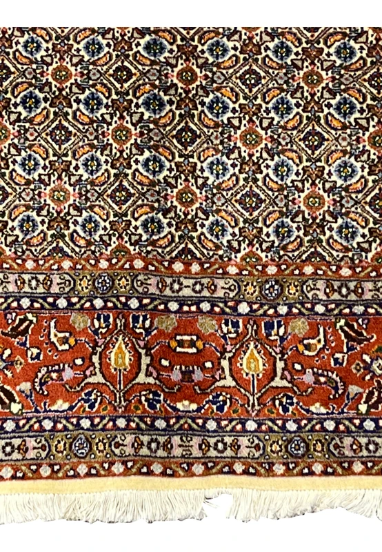 Bottom edge with ivory fringes and rust red border adorned with flowers.