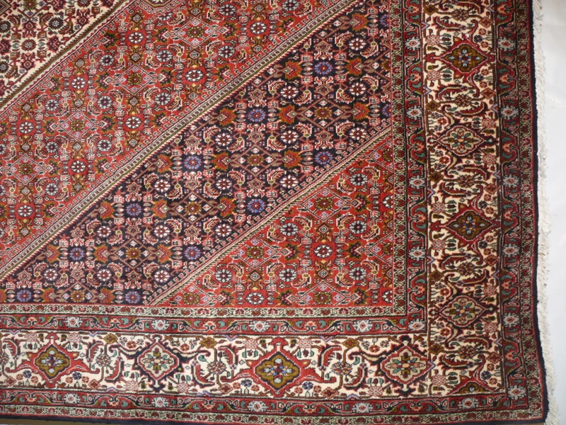 Edge detail of Persian Bijar rug 6'8 x 10'6 with red field and ivory border motifs