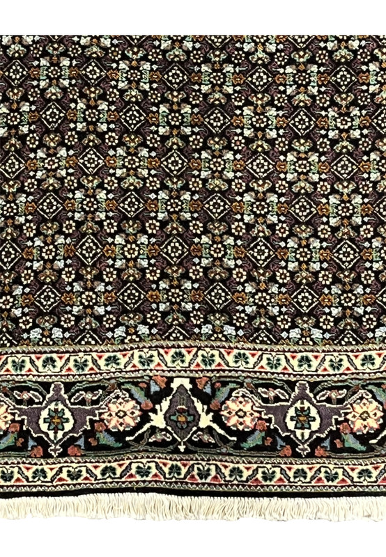 Lower edge of Persian Tabriz Mahi rug with ivory floral border and fringes