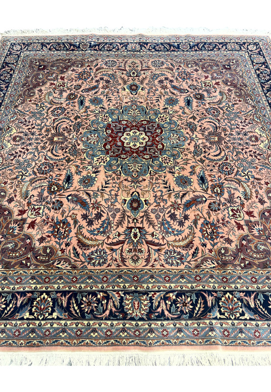 Detailed section of Persian Tabriz rug showing floral field and intricate vine work on salmon background