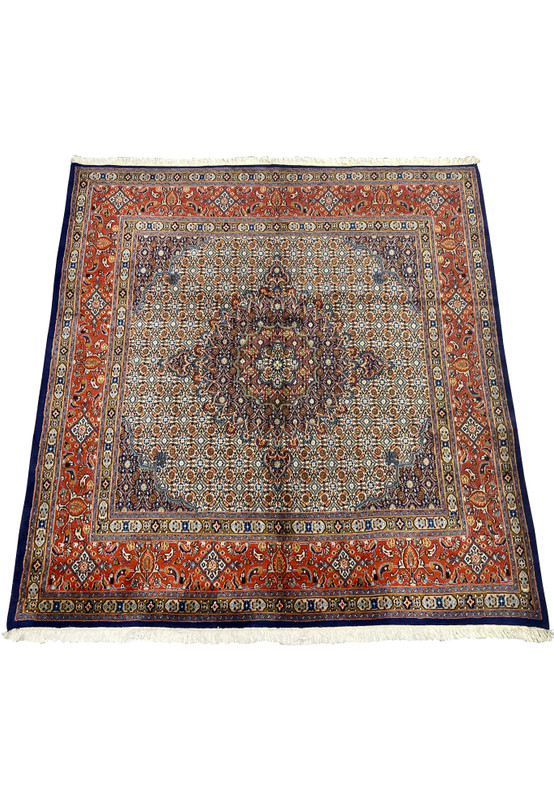 Laid-down view of the Persian Moud rug displaying its precise geometric symmetry, navy medallion center, and fine handknotted motifs across an ivory and rust-red color palette.