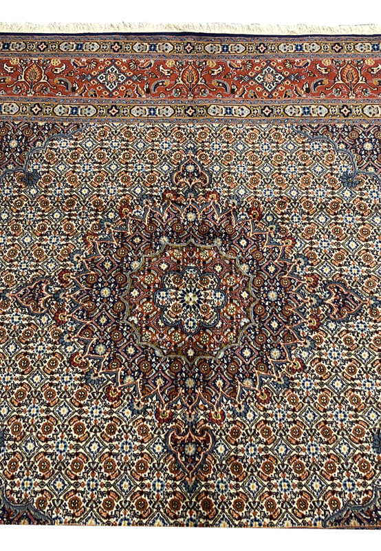 Detailed shot of the medallion with deep navy and rust tones framed by ivory petals, showing the classic Moud composition blending symmetry and fine color gradation.