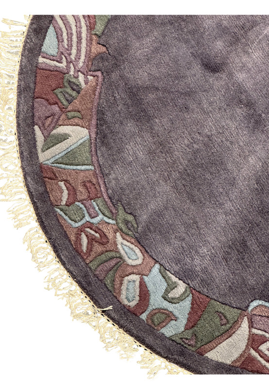 Detailed view of the rug’s edge showing the carved wool texture, light cream fringe, and border design blending earthy tones of olive, mauve, and taupe.
