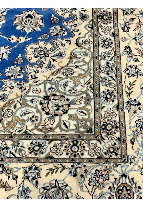 Inner border of Nain rug with fine floral scrollwork in ivory, pale blue, and taupe on royal blue background