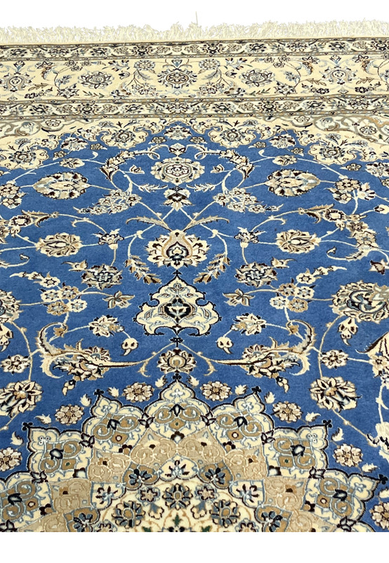 Upper border of Persian Nain rug highlighting ivory background and floral scroll pattern