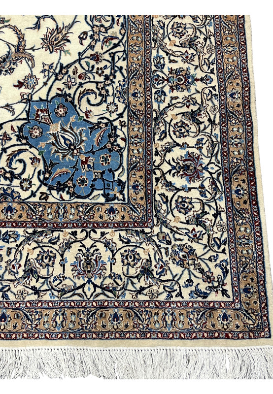 Detailed look at the border of the Persian Nain 4 LA Habibian rug featuring scrolling vines, beige and gold accents, and a thin crimson guard line.