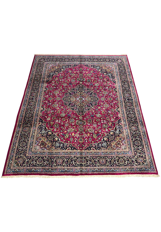 Top full view of Persian Mashad red wool rug showing floral medallion and navy borders.