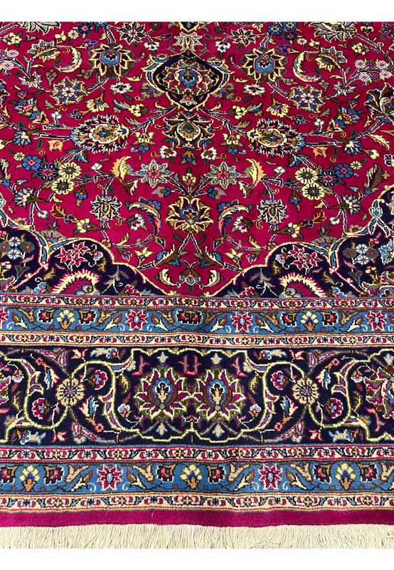 Lower border detail of Persian Mashad rug with navy field, sky blue guard border, and floral motifs.